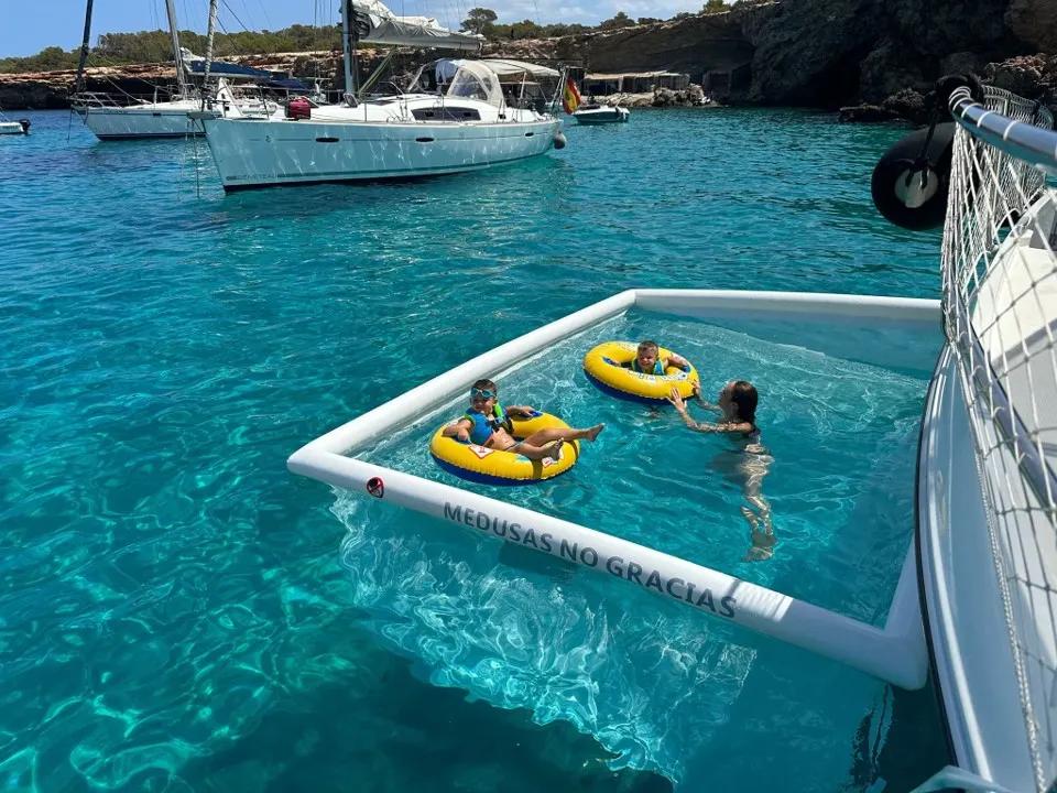 Children playing in anti-jellyfish pool in turquoise waters of Menorca